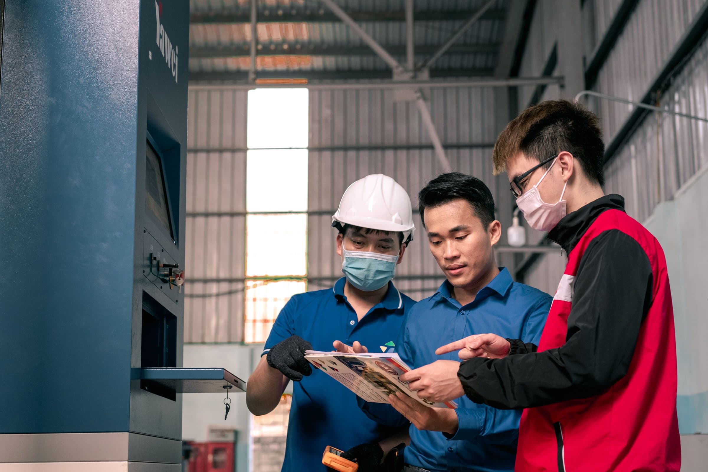 A team of workers reviewing a work order together on a factory floor